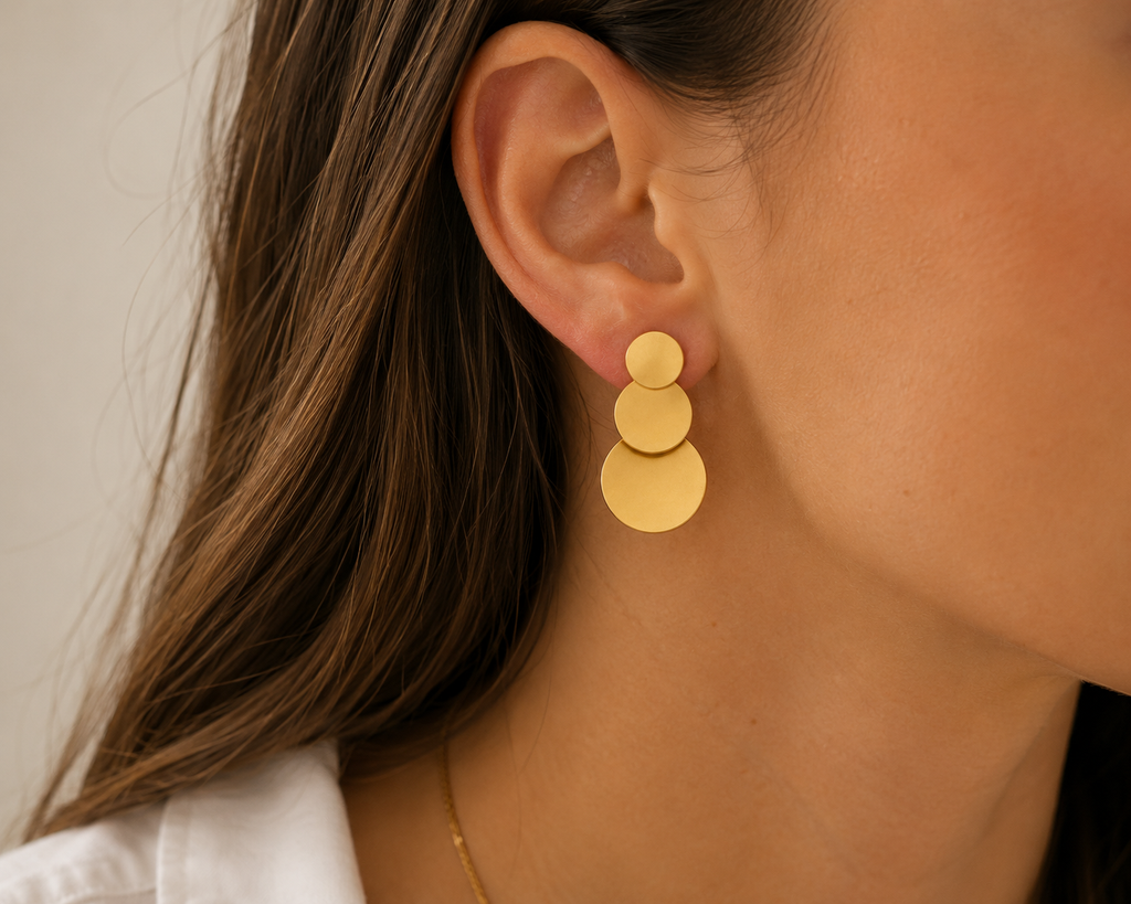 Boucle d’oreille dorée à trois disques NIRMEN portée à l’oreille